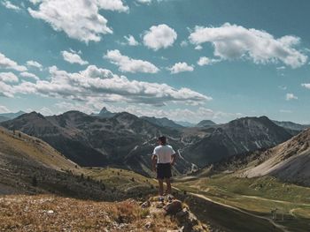 Rear view of man standing on mountain against sky