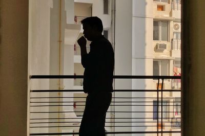 Side view of silhouette man standing against window in building