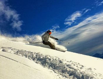 Man skiing on snow covered mountain against sky