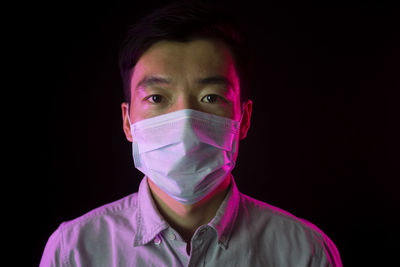 Portrait of young man against black background
