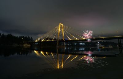 Illuminated bridge over river against sky at night