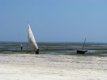 Sailboat on beach against clear sky