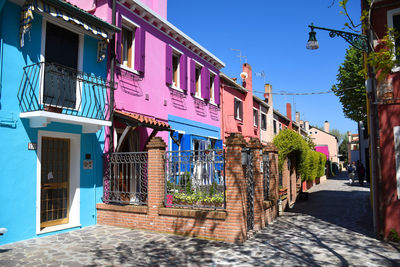 Alley amidst buildings in city against clear blue sky