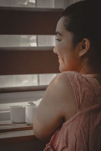 Side view of young woman sitting at home