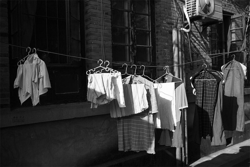 building exterior, architecture, built structure, hanging, low angle view, window, building, house, clothesline, residential building, residential structure, no people, sunlight, drying, day, outdoors, laundry, clothing, city, balcony