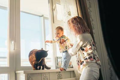 Mother holding son by cat at home