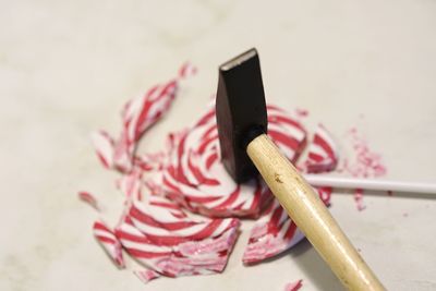 Hammer breaking lollipop on white table