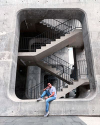 Full length of man sitting by building