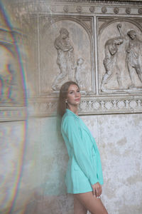 Young woman standing against wall