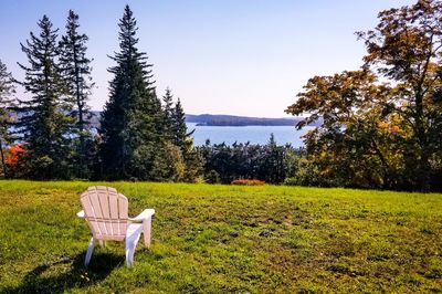 Empty chairs and tables on field against sky