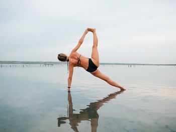 Full length of young woman standing on sea shore against sky