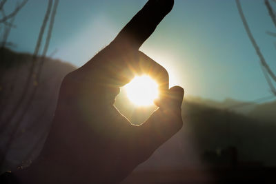 Close-up of hand holding sun against sky during sunset