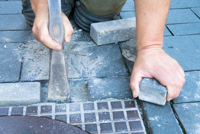 Man removing cobblestones by manhole