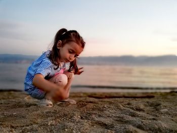 Girl on beach against sky during sunset