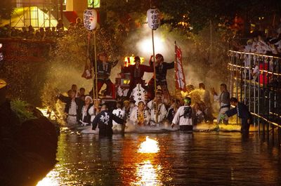 Group of people in illuminated water at night