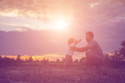 Side view of couple kissing against sky during sunset