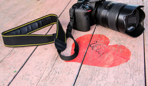 High angle view of dslr camera by red heart shape on table