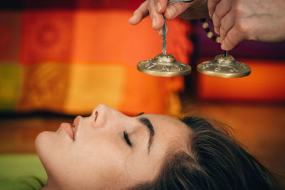 Cropped hands of therapist holding bells by young woman at spa