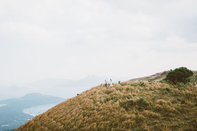 Rear view of people walking on mountain against sky