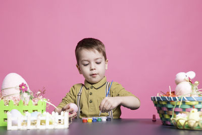 Portrait of boy playing with toy against yellow background