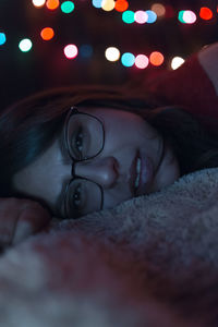 Close-up of young woman wearing eyeglasses lying on blanket