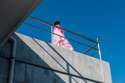 Low angle view of man against clear blue sky