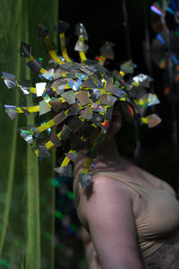 Close-up of a young woman standing in the forest in reflective mask near a green transparent fabric 