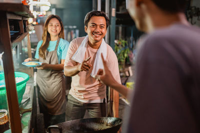 Portrait of smiling young woman standing in cafe