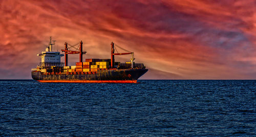 Ship in sea against sky during sunset