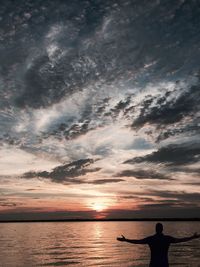 Silhouette man standing against sea during sunset