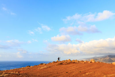  man on rock by sea against sky