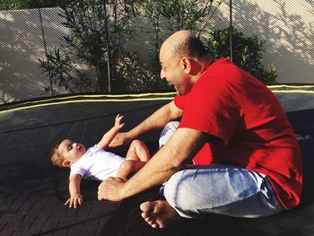 Father playing with baby boy on trampoline