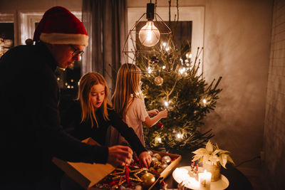 Father and daughters decorating christmas tree