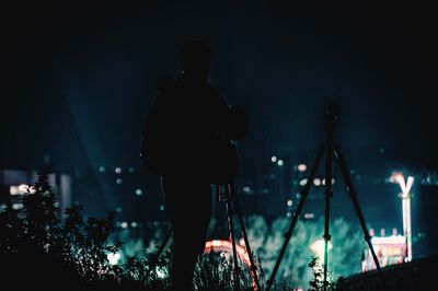 Rear view of silhouette man against illuminated city at night