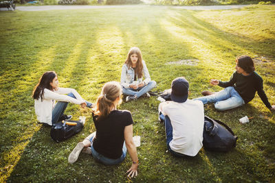 High angle view of male and female teenagers relaxing on grass