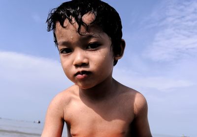 Portrait of shirtless boy against sky