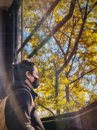 Portrait of young man looking through window