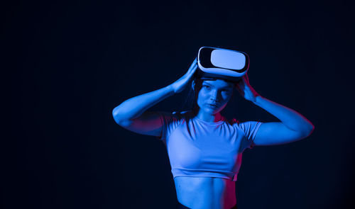 Young woman holding camera against black background