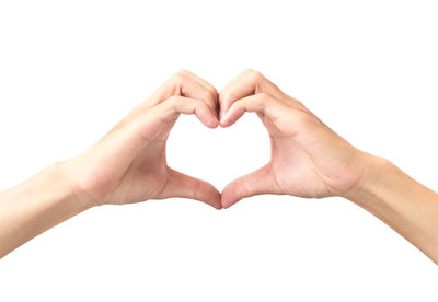 Close-up of hand holding heart shape over white background