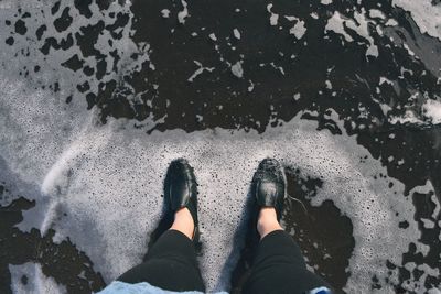 Low section of person standing on wet land