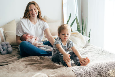 Full length of happy family relaxing on bed at home