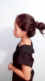 Side view of cute girl standing against white background