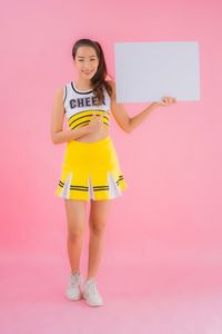 Portrait of woman standing against pink background