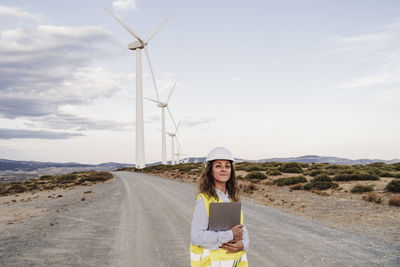 Confident engineer with laptop at wind farm