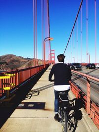 Rear view of woman walking on bridge against clear sky