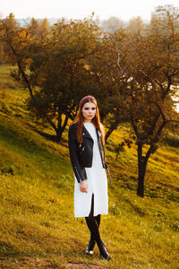 Portrait of beautiful young woman standing on field