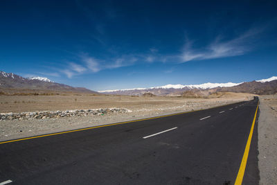 Road by landscape against blue sky