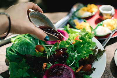 Close-up of hand holding vegetables on table