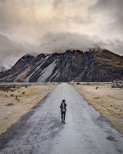 Man on mountain road against sky