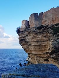 Rock formations by sea against sky